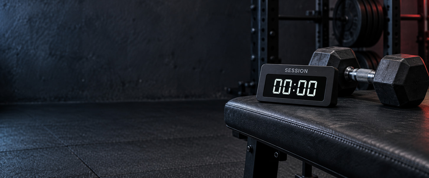 Digital session timer reading 00:00 beside a dumbbell on a workout bench.